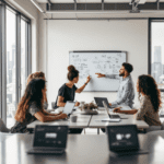 A group of diverse professionals in a bright office setting collaborating at a table. Laptops show AI tools such as ChatGPT and Trello, while one person types and another points to a whiteboard with notes, illustrating teamwork in an innovative environment.